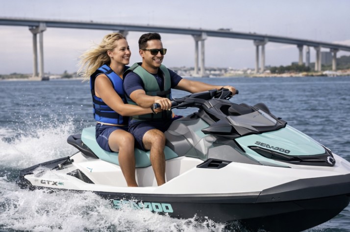 Couple riding a Sea-Doo jet ski near Coronado Island with the Coronado Bridge and San Diego Bay in the background.